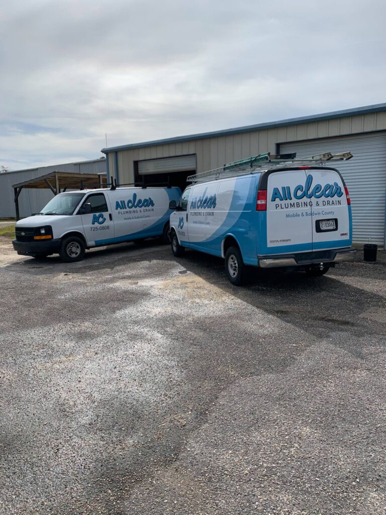 Two All Clear Plumbing trunks parked outside of a commercial area